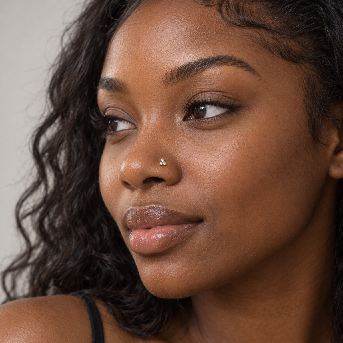 Black model wearing JOAJOA 10L petite gold three-stone L-shaped nose stud