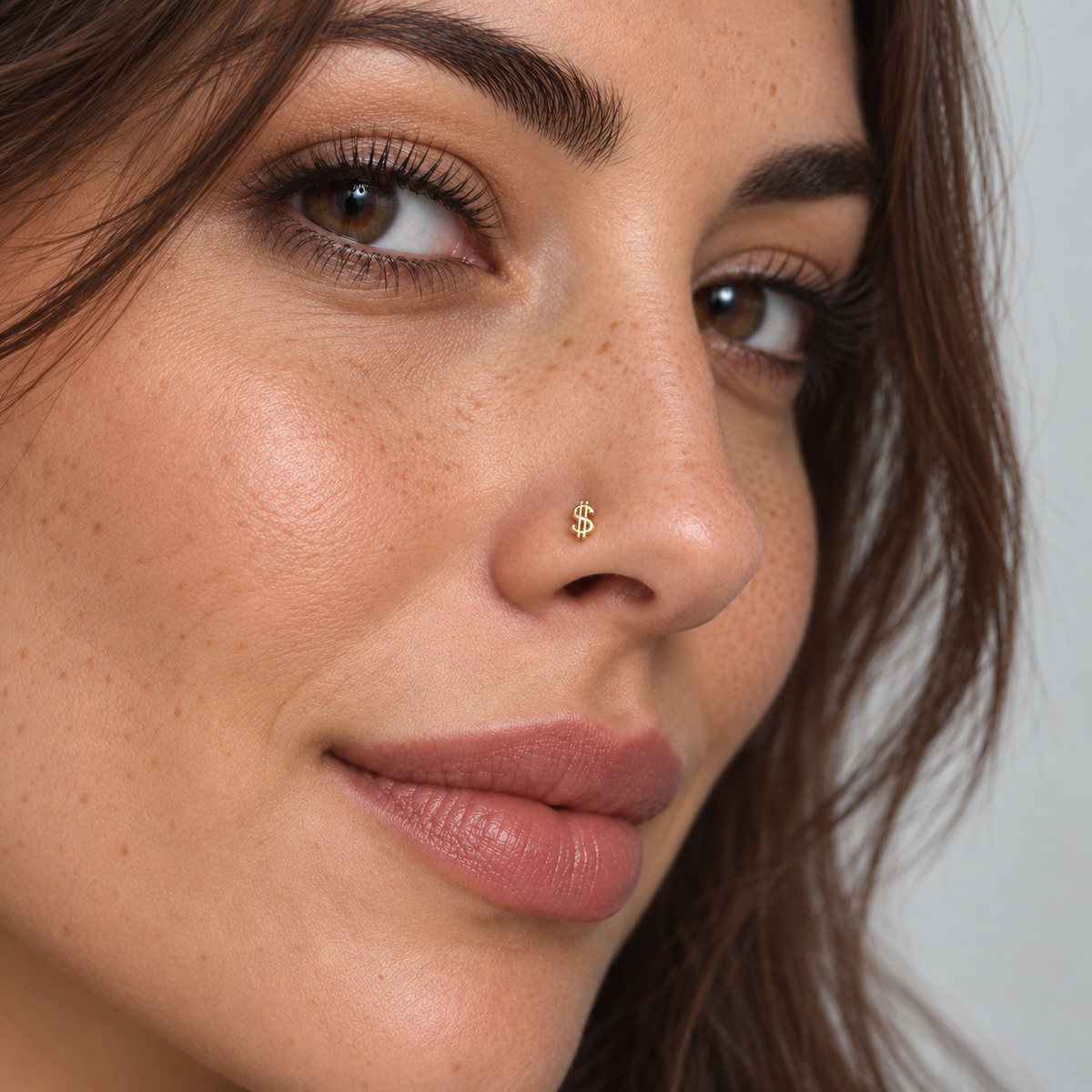 Model naturally wearing a petite gold dollar sign L-shape nose stud