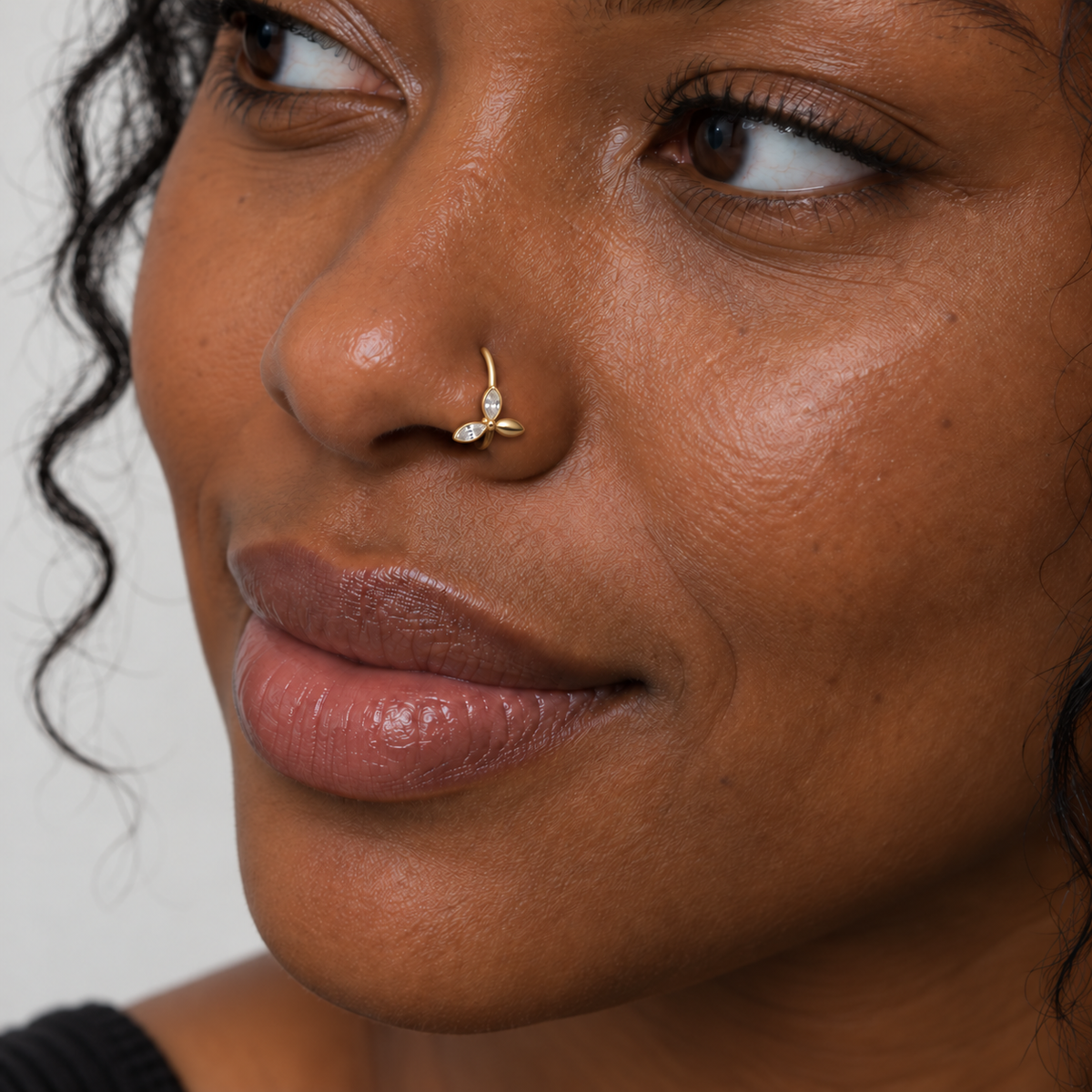 Black model wearing JOAJOA 74 petite gold three-petal butterfly hoop nose ring