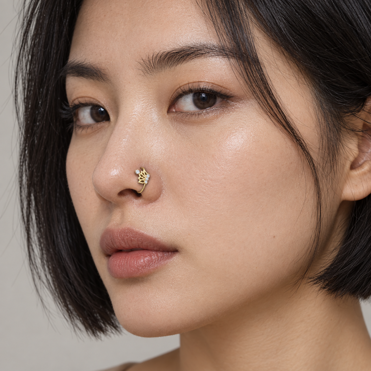East Asian model wearing JOAJOA 75 petite gold crystal crown B hoop nose ring