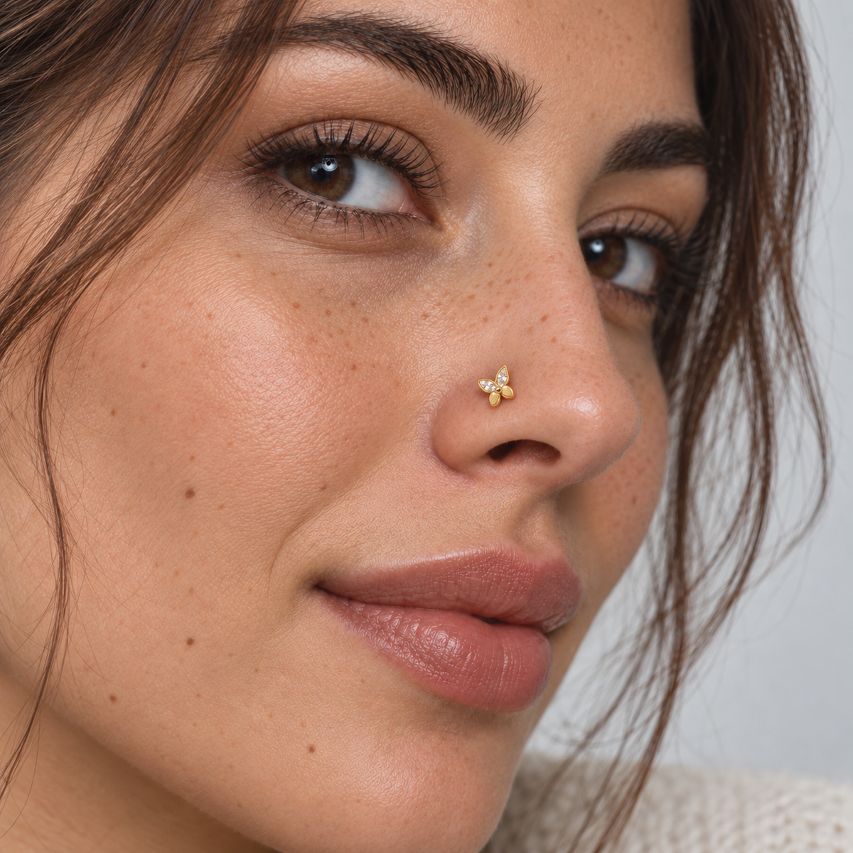Freckled model wearing JOAJOA 76 petite gold butterfly L-shape nose stud